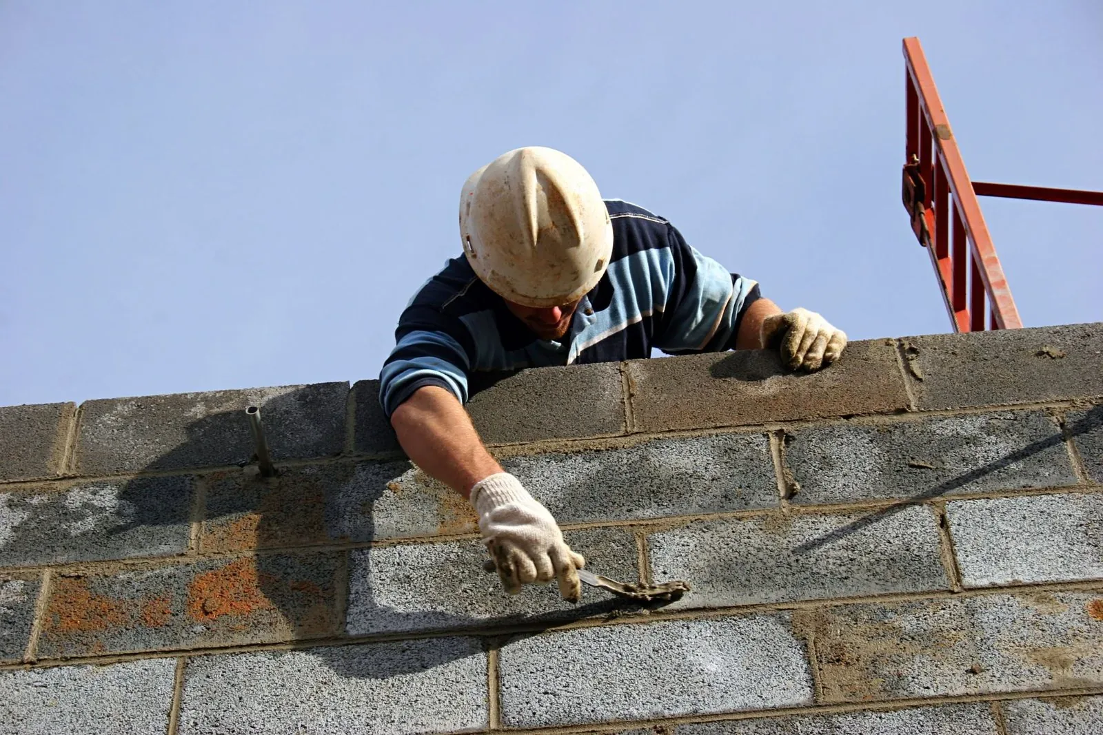 Maçon de Maçonnerie 64 montant un mur en blocs